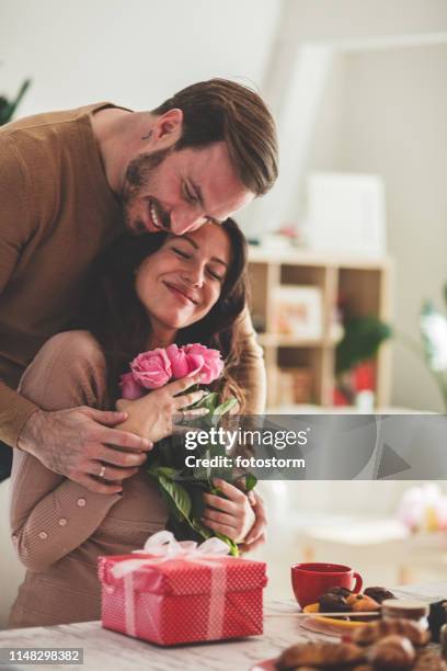 hombre adulto medio dando a su novia flores y regalo - día de san valentín fotografías e imágenes de stock