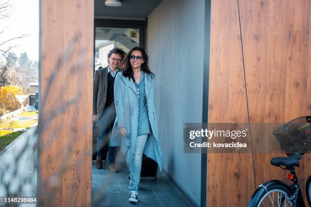 caucasian couple departing their apartment with suitcases - suitcase couple stock pictures, royalty-free photos & images