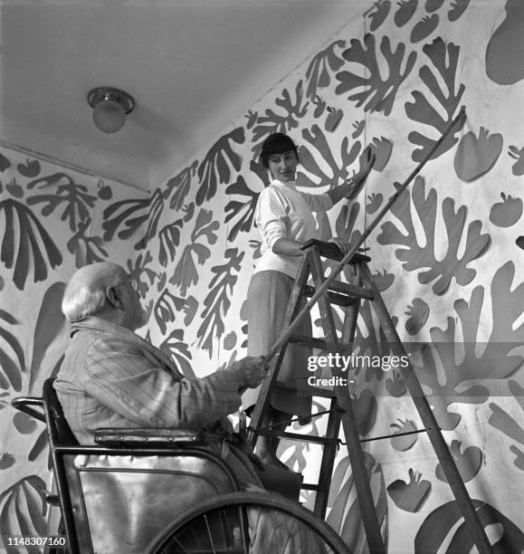 Le peintre et sculpteur français Henri Matisse travaille dans son atelier au Régina, à Nice, en 1952, devant l'oeuvre monumentale en papiers gouachés...