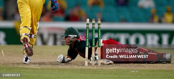 Zimbabwean batsman Heath Streak is sprawled on the ground after he has been stumped by Australian wicketkeeper Adam Gilchrist during their one-day...