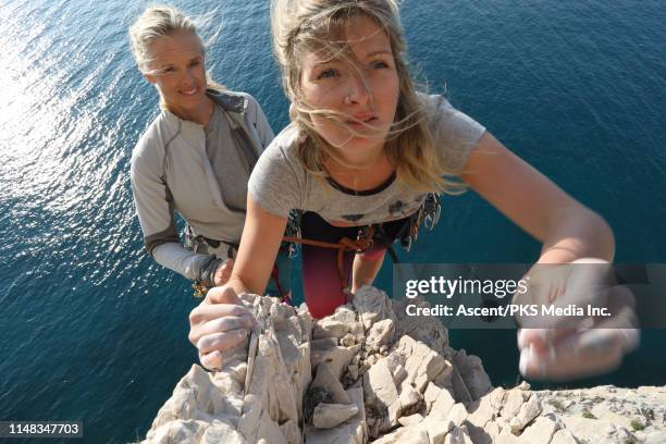 two women climb pinnacle above the sea - escalar rochas imagens e fotografias de stock