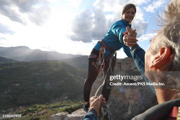 female climber ascends to summit of pinnacle, above hills - winning team emerging stock pictures, royalty-free photos & images