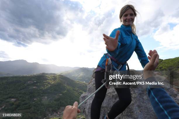 female climber ascends to summit of pinnacle, above hills - winning team emerging stock pictures, royalty-free photos & images