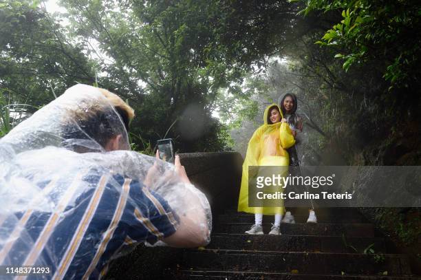 man taking a photo of friends in heavy rain - rain poncho stockfoto's en -beelden