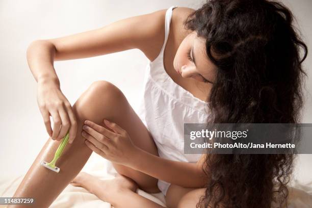 young woman shaving legs - scheren stockfoto's en -beelden