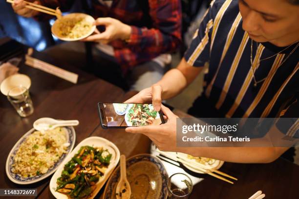 young man taking a picture of his street food dinner - taiwanese culture stockfoto's en -beelden