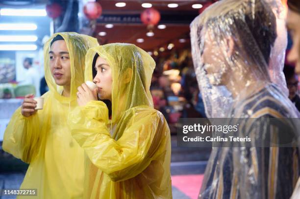 tourists sampling street food in the rain - poncho stock pictures, royalty-free photos & images