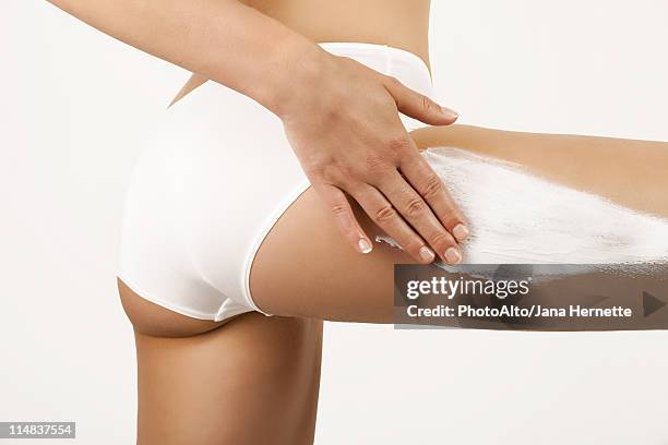 woman applying moisturizer to thigh, cropped - thigh human leg stock pictures, royalty-free photos & images