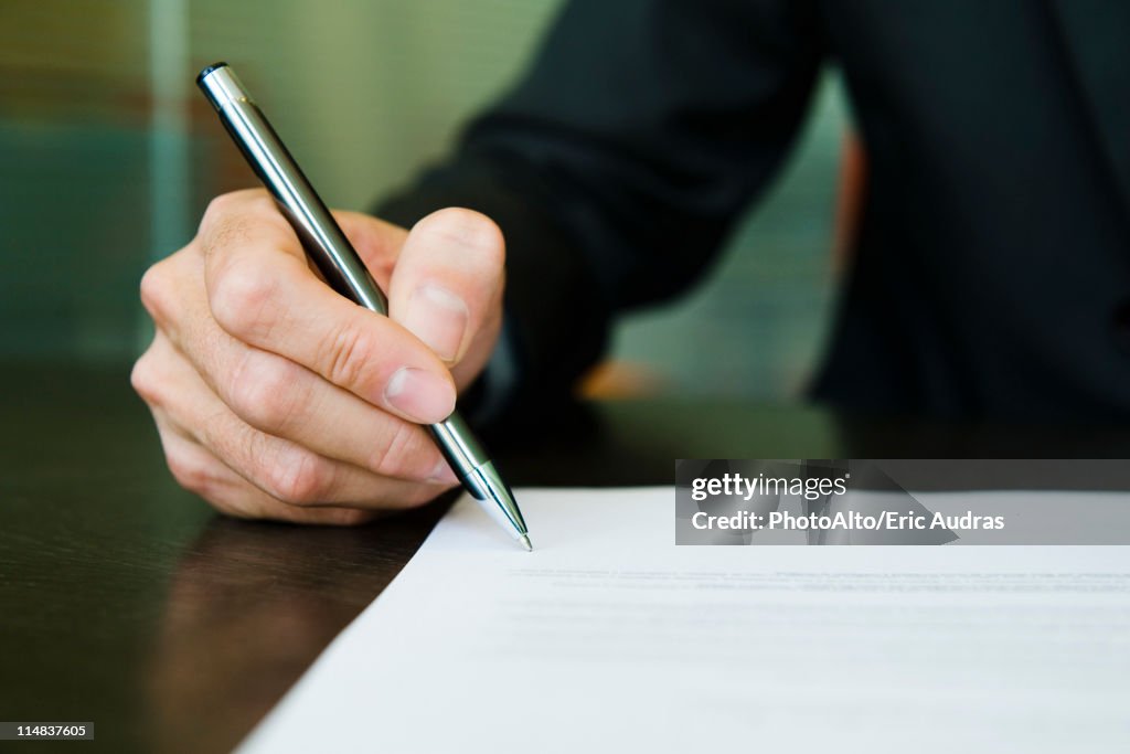 Businessman signing paperwork, cropped