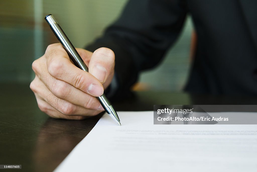 Businessman signing paperwork, cropped