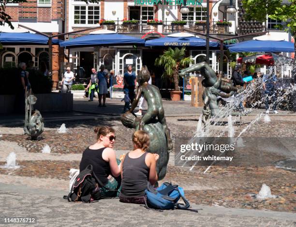 duas mulheres que sentam-se por uma fonte em universitätsplatz, rostock - rostock - fotografias e filmes do acervo