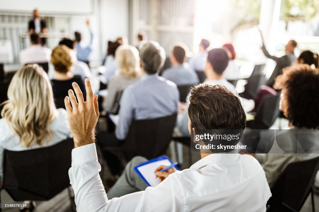Rückblick auf einen Geschäftsmann, der auf einem Seminar die Hand legt.
