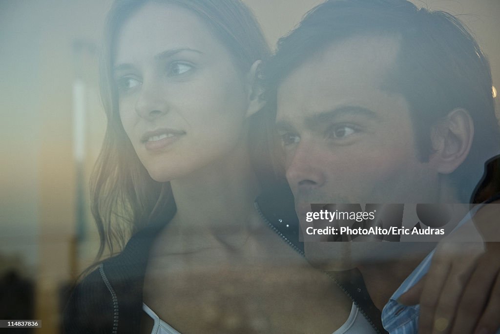 Couple looking through window, portrait
