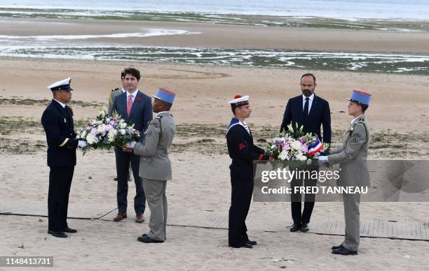 Canadian Prime Minister Justin Trudeau and French Prime Minister Edouard Philippe are presented wreaths of flowers during an international ceremony...