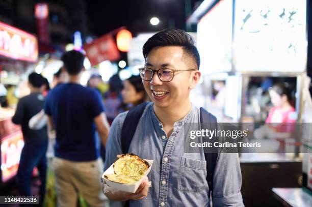 man holding grilled scallops in a night market - taipei market stock pictures, royalty-free photos & images