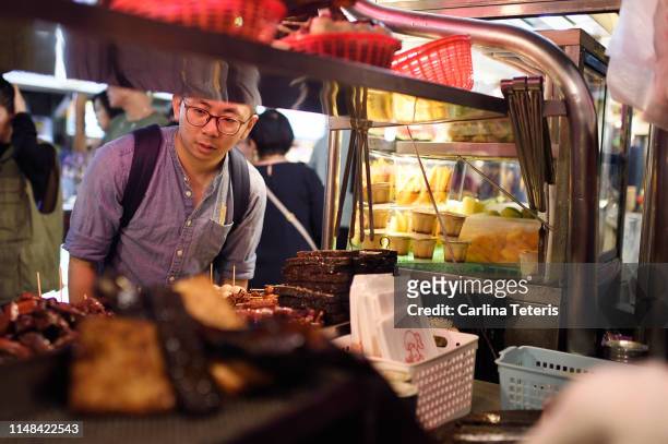 man looking through a street food stall - market stall stock-fotos und bilder
