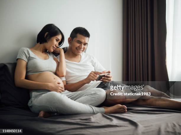 pareja embarazada viendo video de ultrasonido en el teléfono inteligente - baby touching belly fotografías e imágenes de stock