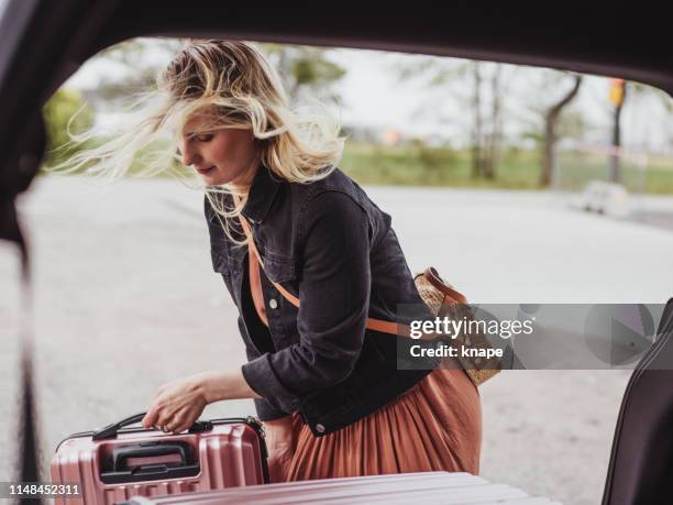 vrouw verpakking haar auto met bagage zakjes klaar voor reis - achterbak-van-auto stockfoto's en -beelden