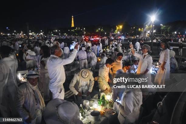 People dressed in white take part in the 31st edition of the "Diner en Blanc" event being held in the Tuileries Gardens in Paris on June 6, 2019. -...