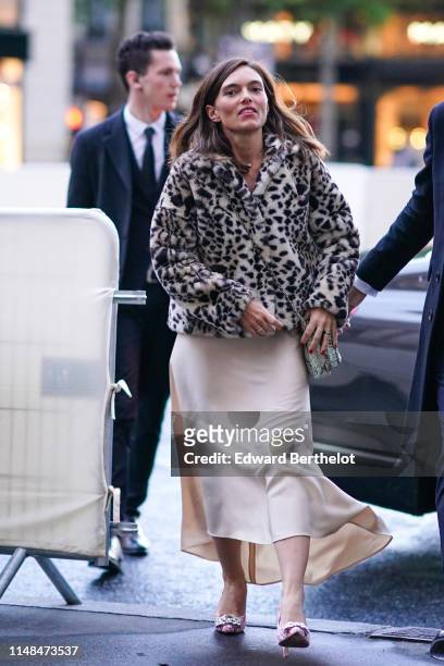 Guest wears a white and black cheetah print faux-fur jacket, a grey python skin bag, a lustrous beige satin asymmetric skirt, pink tweed bejewelled...