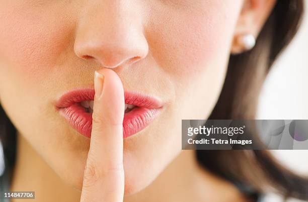 young woman with finger on lips, close-up - solo una donna giovane foto e immagini stock