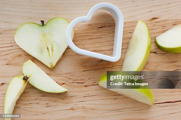 heart shaped apples with cutter on chopping board - apple slice stock-fotos und bilder