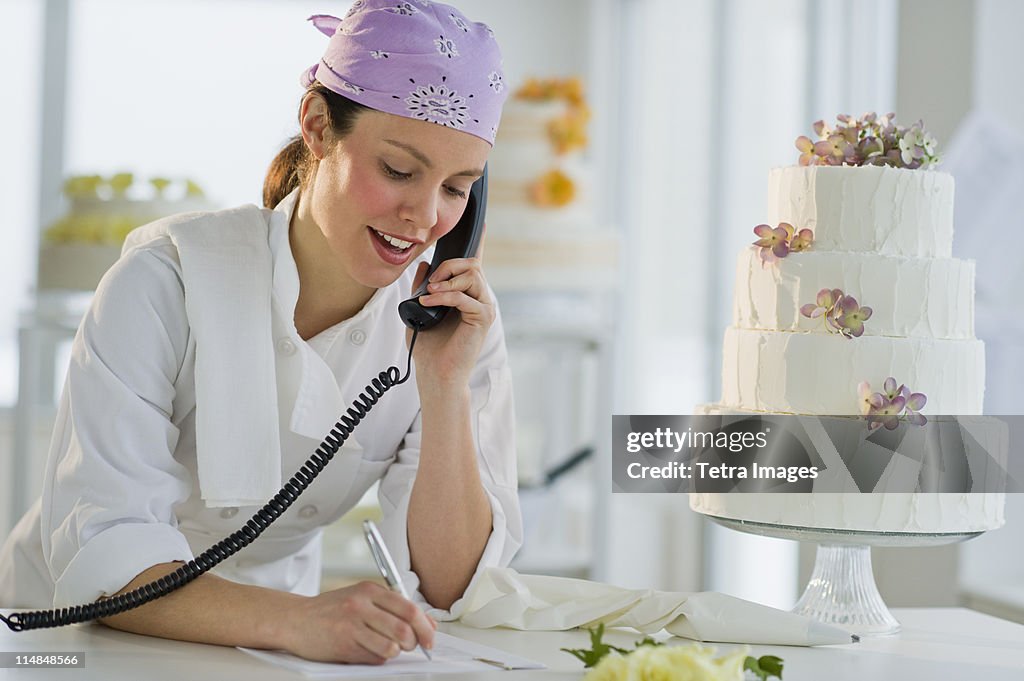 USA, New Jersey, Jersey City, Happy young woman taking order near wedding cake