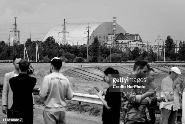 Image was converted to black and white) Visitors look on the protective shelter over the remains of the nuclear reactor Unit 4 at the Chernobyl...