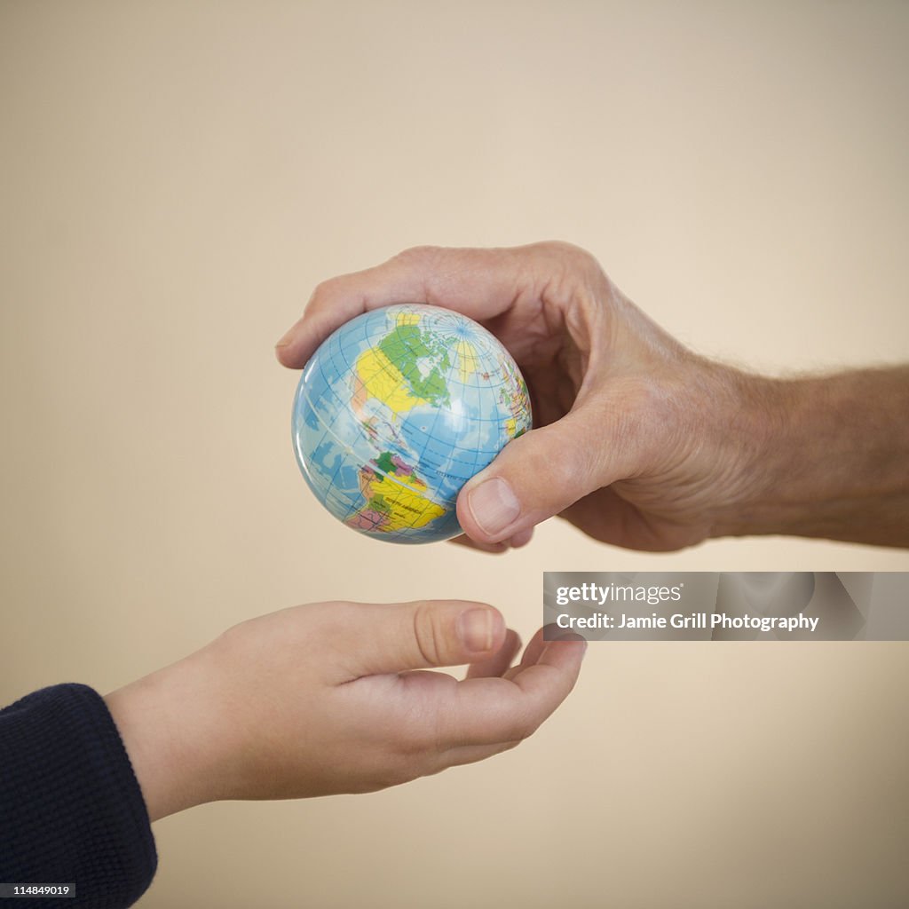 USA, New Jersey, Jersey City, close up of hands of grandfather and grandson (8-9) with small globe