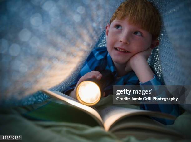 usa, new jersey, jersey city, boy (8-9) reading book under bed covers - bedtime stock pictures, royalty-free photos & images