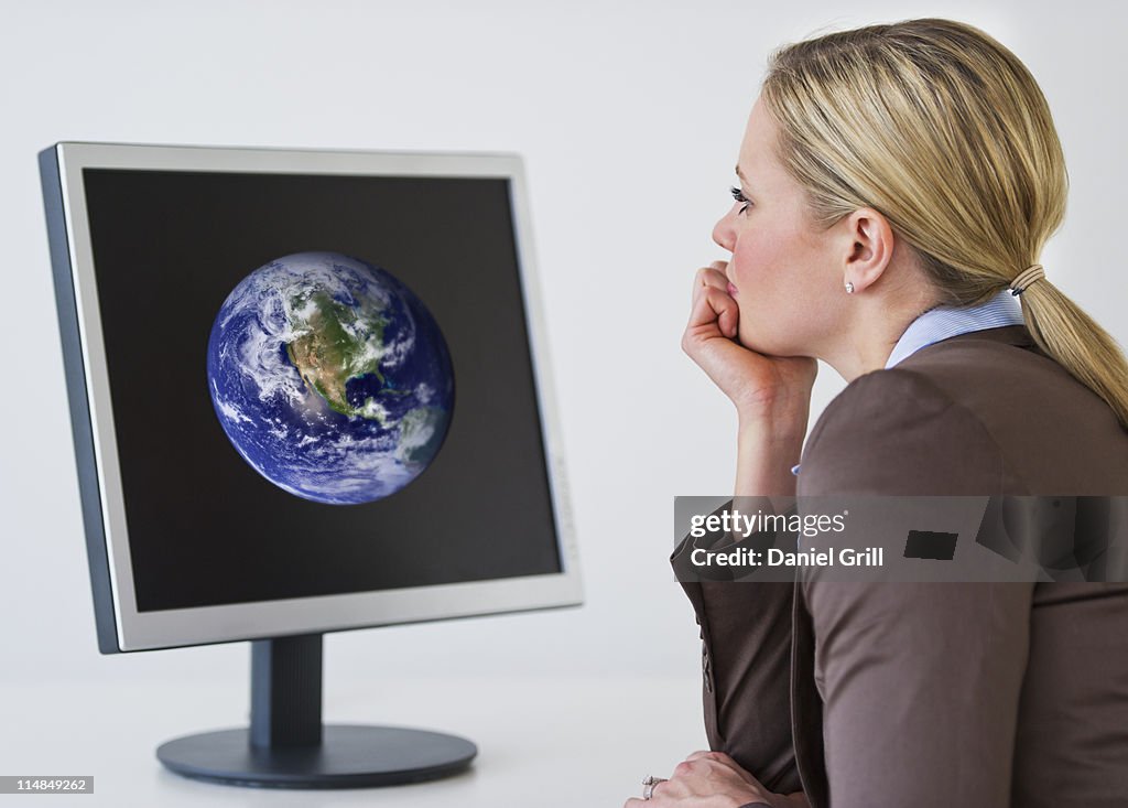 Businesswoman looking at monitor with globe