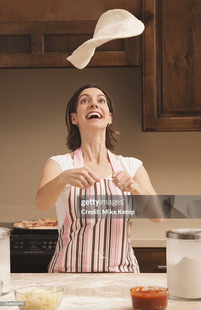 USA, Utah, Lehi, Woman tossing dough in kitchen