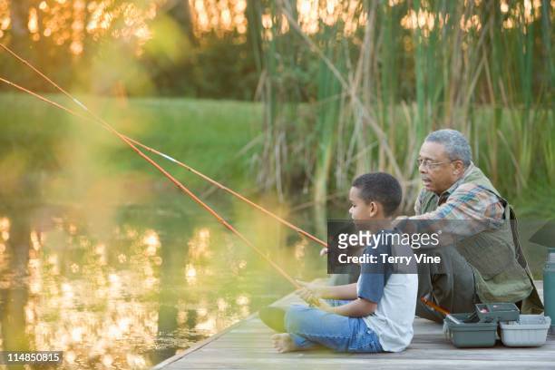 grandfather and grandson fishing on pier - multigenerational multiracial group stock pictures, royalty-free photos & images