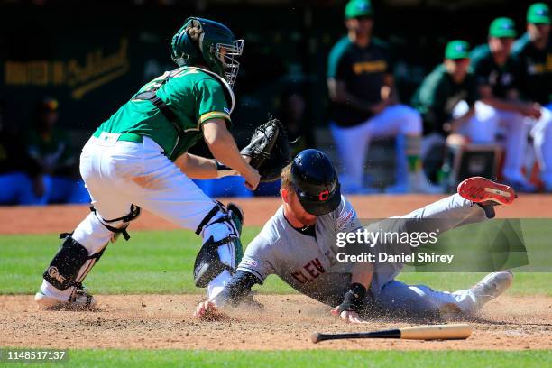 Jordan Luplow of the Cleveland Indians slides into home before the tag by Ramon Laureano of the Oakland Athletics during the ninth inning at...