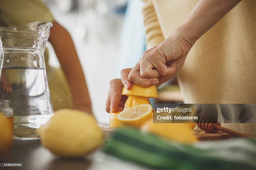 Woman squeezing lemon at the kitchen counter