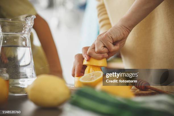 woman squeezing lemon at the kitchen counter - ascorbic acid stock pictures, royalty-free photos & images