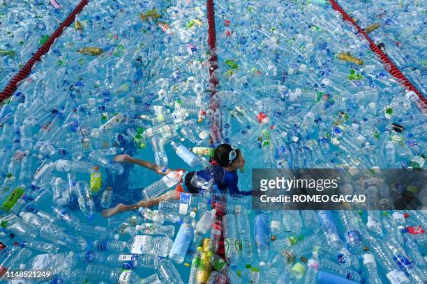 Child swims in a pool filled with plastic bottles during an awareness campaign to mark the World Oceans Day in Bangkok on June 8, 2019.