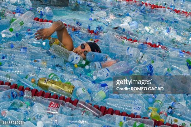 Participant swims in a pool filled with plastic bottles during an awareness campaign to mark the World Oceans Day in Bangkok on June 8, 2019.