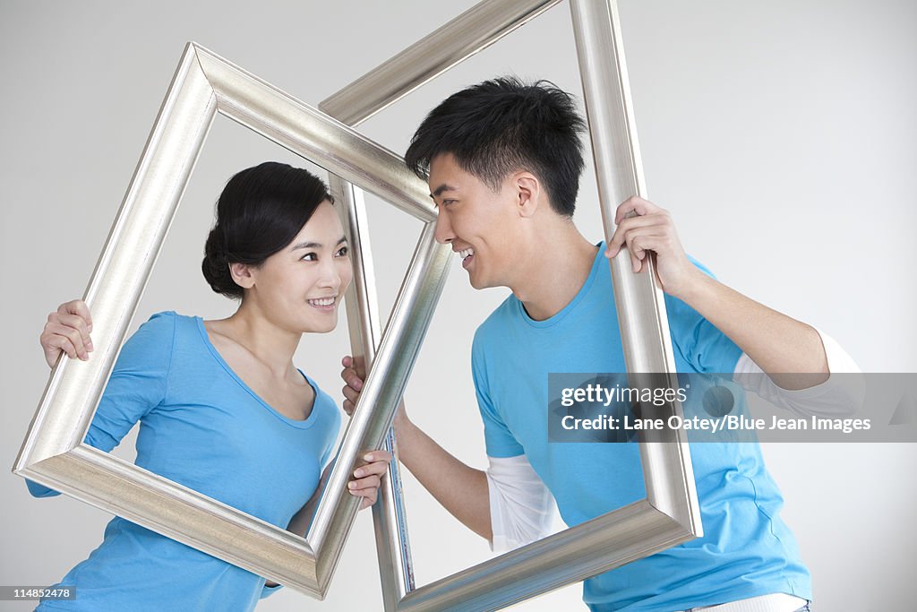 Couple having fun with picture frames