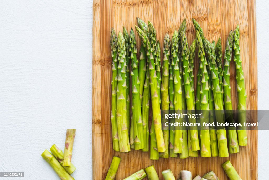 Asperges op een houten snijplank, bovenaanzicht, close-up op witte achtergrond. Koken, vegetarisch, gezond eten