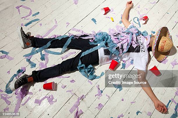 man lying on floorboard covered with streamers at party - passed out drunk stockfoto's en -beelden