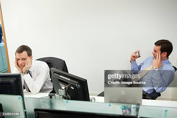 businessman using smartphone, male colleague looking sideways - ignorance foto e immagini stock