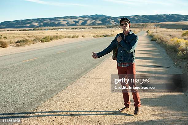 young man hitchhiking at roadside - hitchhiking 個照片及圖片檔