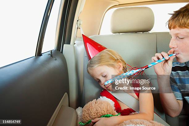 boy blowing party blower in back seat of car - irritation stock pictures, royalty-free photos & images