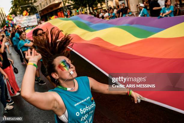 Participant dances while holding a large rainbow flag during the Athens Gay Pride in Athens on June 8, 2019. - Thousands marched in the 15th annual...