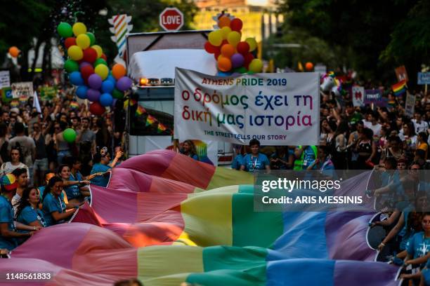 People march with a large rainbow flag as they take part in the Athens Gay Pride in Athens on June 8, 2019. - Thousands marched in the 15th annual...