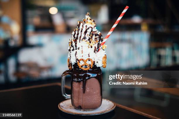 chocolate mega milkshake topped with cream, served in a mason jar - overflowing glass stock-fotos und bilder