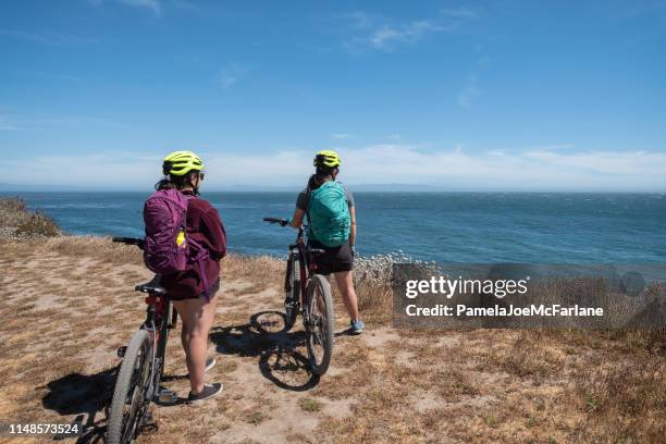 eurasian, millennial sisters riding bicycles along california seaside bluff - santa cruz california beach stock pictures, royalty-free photos & images