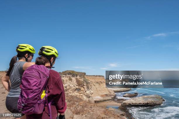 multi-ethnic cycling sisters taking break to enjoy california coast view - santa cruz california beach stock pictures, royalty-free photos & images