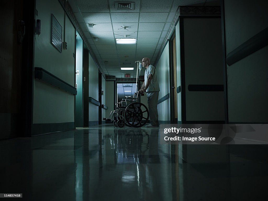 Male nurse with empty wheelchair and intravenous drip